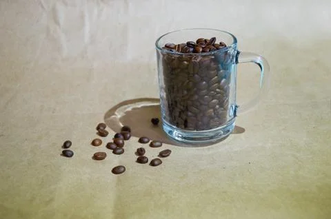 Roasted coffee beans are placed in and around a clear glass Cup Stock Photos