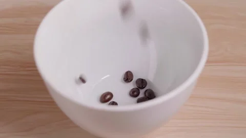 Roasted coffee beans are poured into a slow-motion measuring cup, ready to be Stock-Footage 168519125