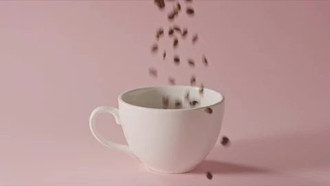 Roasted coffee beans are pouring into ceramic cup and on a table. Stock Footage 129634323