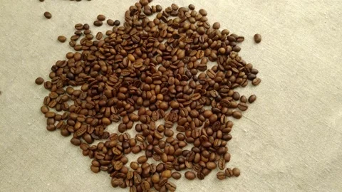 Roasted coffee beans are sprinkled on a textile napkin, rotating slowly Video stock 150938934