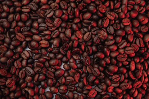 Roasted coffee beans background in red color close-up Stock Photos