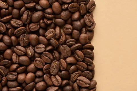 Roasted coffee beans on beige background with copy space. Close up top view. Stock Photos