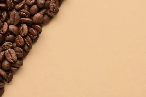 Roasted coffee beans on beige background with copy space. Close up top view. Stock Photos