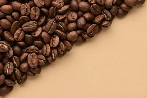 Roasted coffee beans on beige background with copy space. Close up top view. Stock Photos