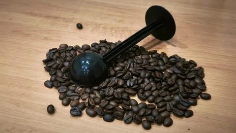 Roasted Coffee Beans with Black Measuring Scoop on Wooden Table Stock Photos