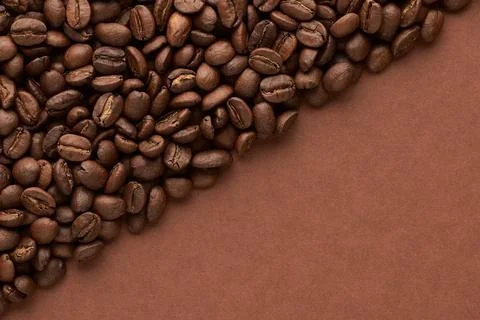 Roasted coffee beans on brown background with copy space. Close up top view. Stock Photos