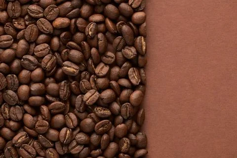 Roasted coffee beans on brown background with copy space. Close up top view. Stock Photos