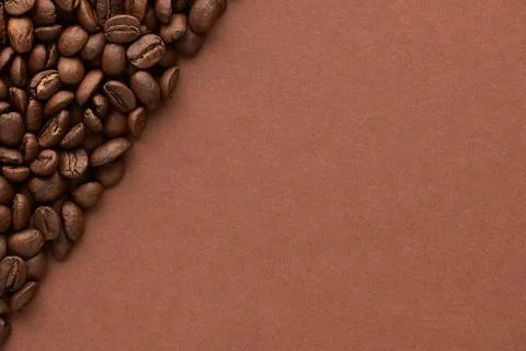 Roasted coffee beans on brown background with copy space. Close up top view. Stock Photos