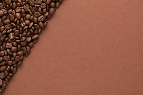 Roasted coffee beans on brown background with copy space. Close up top view. Stock Photos