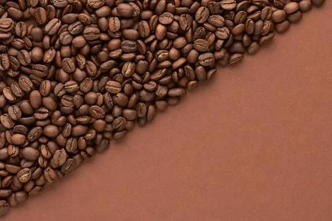 Roasted coffee beans on brown background with copy space. Close up top view. Stock Photos