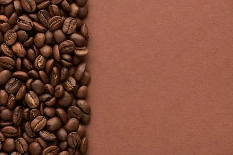 Roasted coffee beans on brown background with copy space. Close up top view. Stock Photos