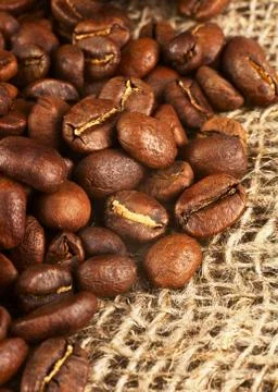 Roasted coffee beans on burlap background. Stock Photos