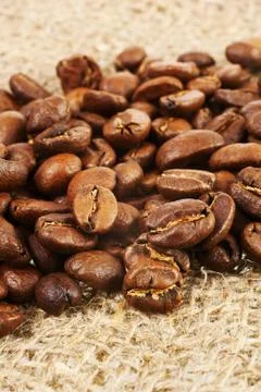 Roasted coffee beans on burlap background. Stock Photos