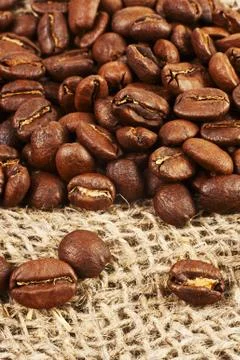 Roasted coffee beans on burlap background. Stock Photos