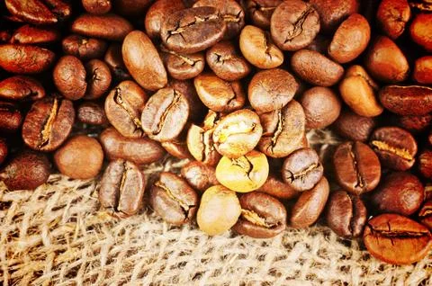 Roasted coffee beans on burlap background. Stock Photos