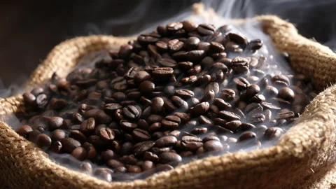 Roasted coffee beans in burlap sack with smoke on top. Video stock 177558550
