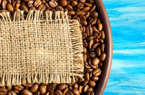 Roasted coffee beans in a ceramic plate on a turquoise background. Stock Photos