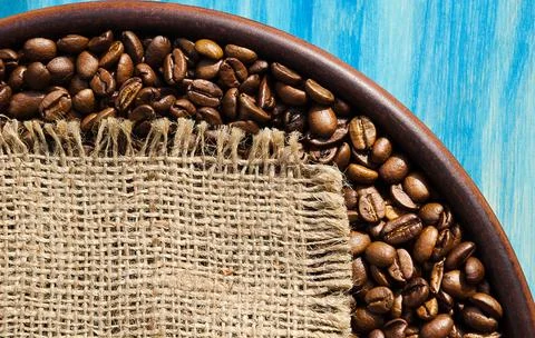 Roasted coffee beans in a ceramic plate on a turquoise background. Foto stock