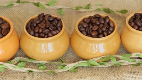 Roasted coffee beans in a clay pots on burlap background, close-up. Stock Footage 201229281
