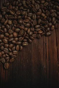 Roasted coffee beans creating an inviting pattern on a dark wood background.. Stock Photos
