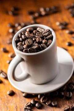 Roasted coffee beans in cup Roasted coffee beans in cup on wooden table. C... Stock-Fotos