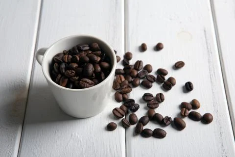 Roasted coffee beans in the cup on a white wooden background Stock Photos