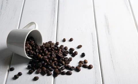 Roasted coffee beans in the cup on a white wooden background Stock Photos