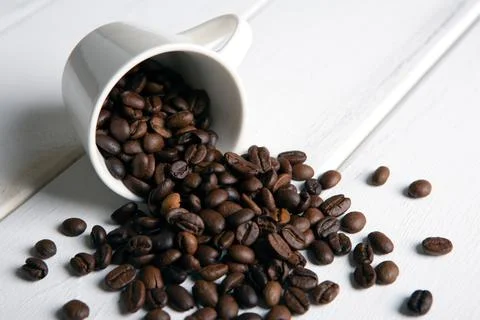 Roasted coffee beans in the cup on a white wooden background Stock Photos