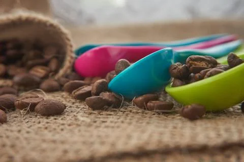 Roasted coffee beans, dose measuring spoons on jute sack Stock Photos