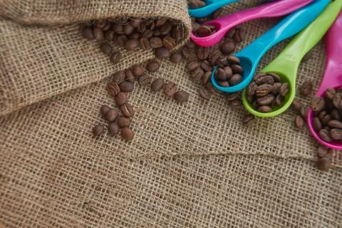 Roasted coffee beans, dose measuring spoons on jute sack Stock Photos