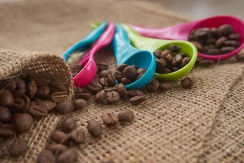 Roasted coffee beans, dose measuring spoons on jute sack Stock Photos