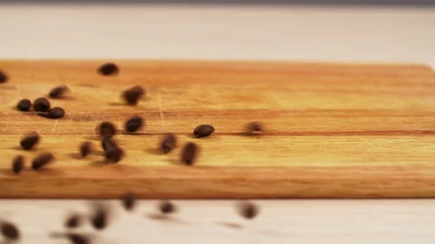 Roasted coffee beans fall on the table close-up and scatter on the 4K board. Stock Footage 114626965