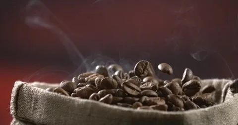 Roasted coffee beans falling into a burlap sack with rising steam in slow motion Stock Footage 342590950