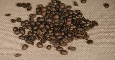 Roasted coffee beans falling on a jute covered table Stockbeeldmateriaal 231573342