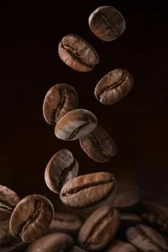 Roasted coffee beans falling on pile. Dark colors Stock Photos
