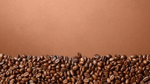 Roasted coffee beans forming a border at the bottom on a brown textured bac.. Stock Photos