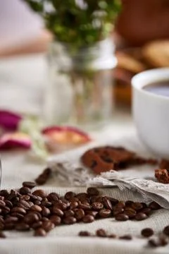 Roasted coffee beans get out of overturned glass jar on homespun tablecloth Stock Photos