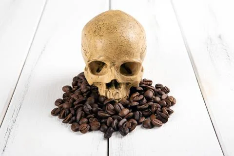 Roasted coffee beans with a human skull as a symbol of danger Stock-Fotos