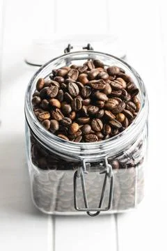 Roasted coffee beans in jar Roasted coffee beans in jar on white table. Co... Stock Photos