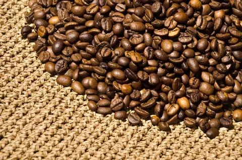 Roasted coffee beans on a knitted pattern in beige raffia. Hand knitted. Stock Photos