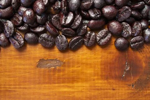 Roasted coffee beans located at the top of the photo on a wooden background Stock Photos