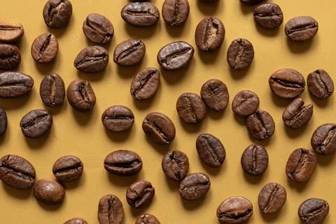 Roasted coffee beans lying on a gold background Stock Photos