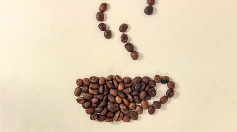 The roasted coffee beans move into the shape of a mug and steam from the drin Stock Photos