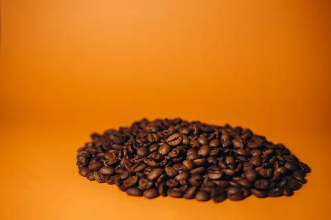 Roasted coffee beans on orange background Stock Photos