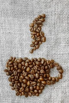 Roasted coffee beans placed in the shape of a cup and placed on sackclothe Stock Photos