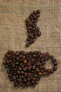 Roasted coffee beans placed in the shape of a cup and placed on sackclothe Stock Photos