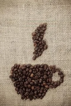 Roasted coffee beans placed in the shape of a cup and placed on sackclothe Stock Photos