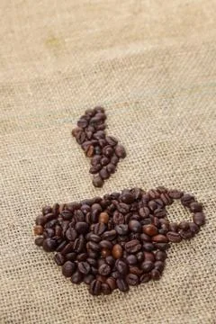 Roasted coffee beans placed in the shape of a cup and placed on sackclothe Stock Photos