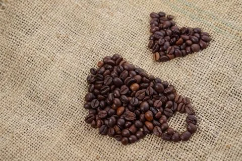 Roasted coffee beans placed in the shape of a cup and placed on sackclothe Stock Photos