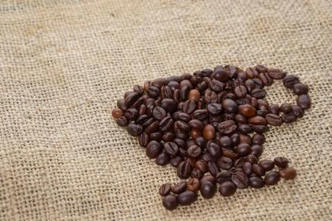 Roasted coffee beans placed in the shape of a cup and placed on sackclothe Stock Photos